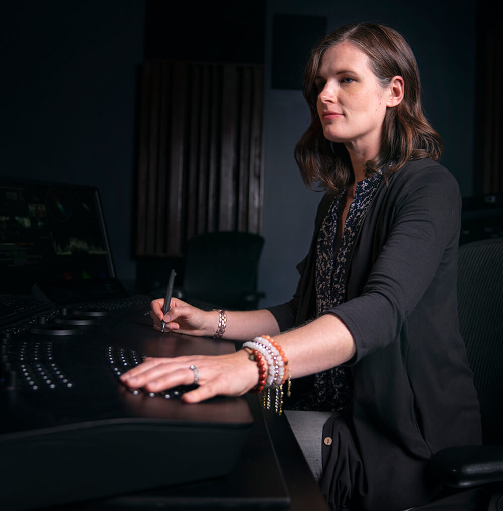 Employee sits at a colorist workstation in a dark theater