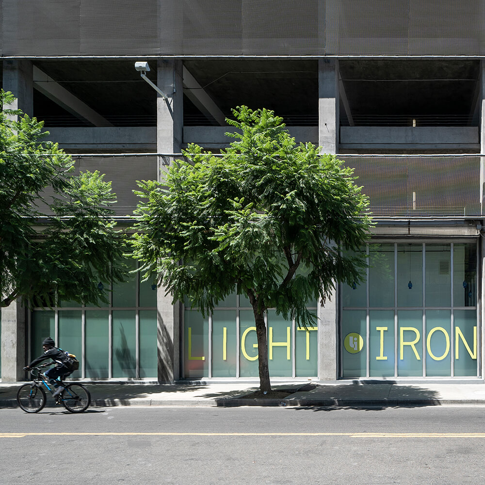 Light Iron building-front with lush trees and a cyclist riding by